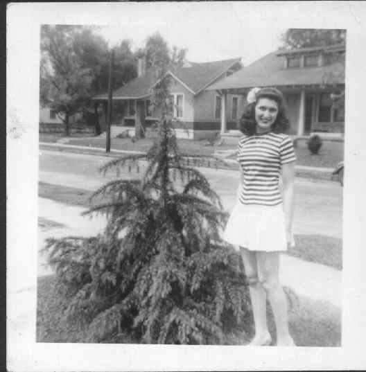 young Margie Goodman in front of a small tree